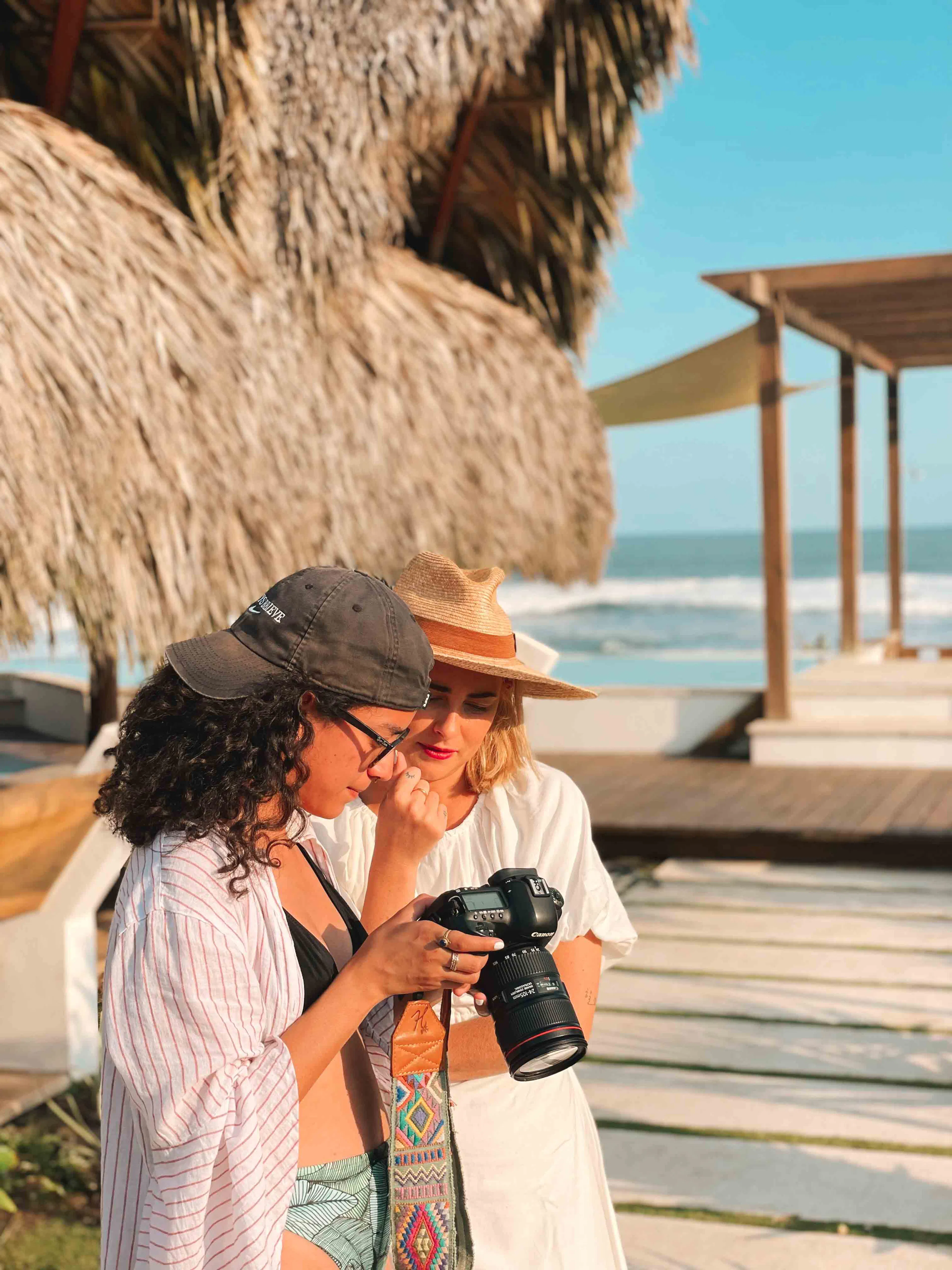 Two women checking photos on a camera on a beach deck