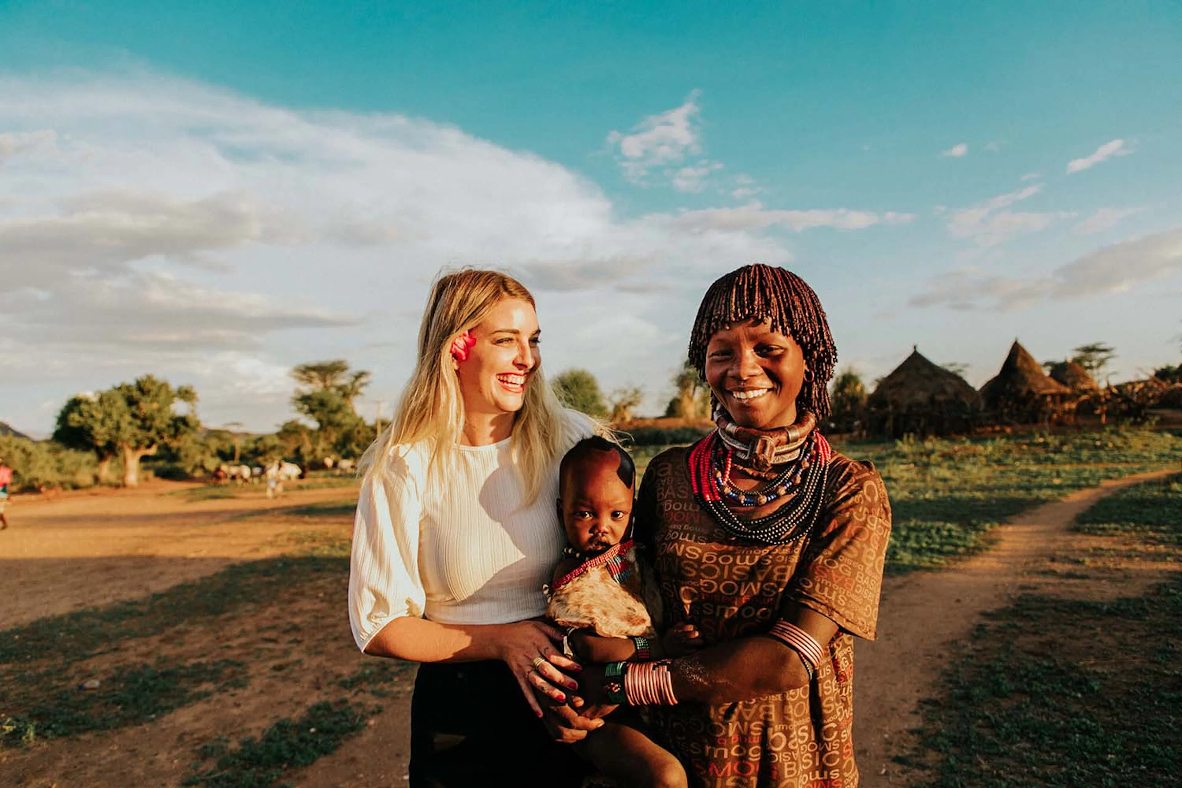 Alyssa Cate standing with a woman holding a child outside a village