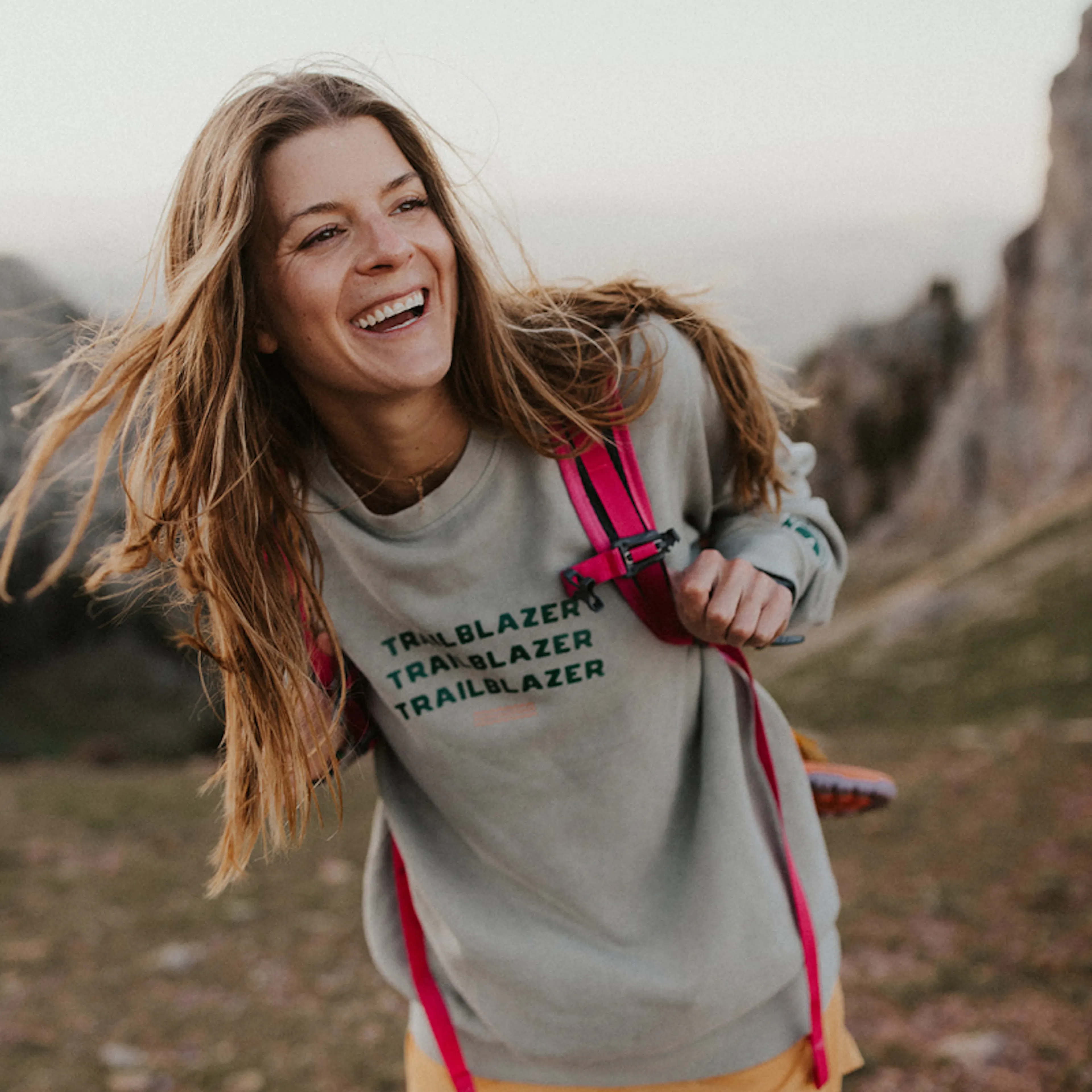 Cassidy Wendell laughing on a mountain trail in a Trailblazer sweatshirt