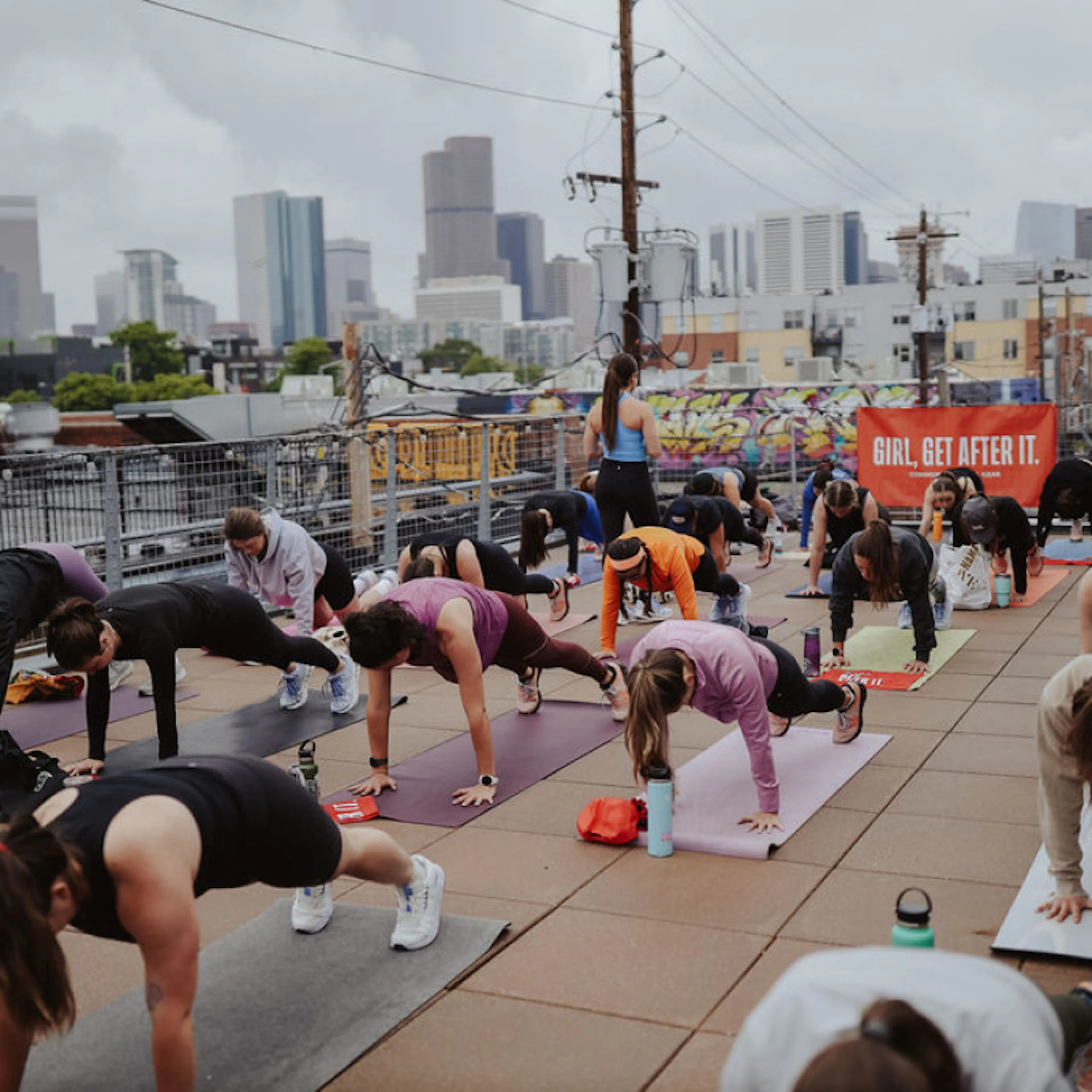 A Girl, Get After It rooftop workout with a city skyline behind