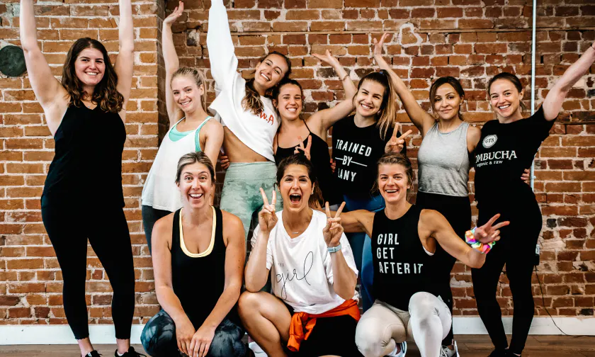 A group of women cheering in front of a brick wall