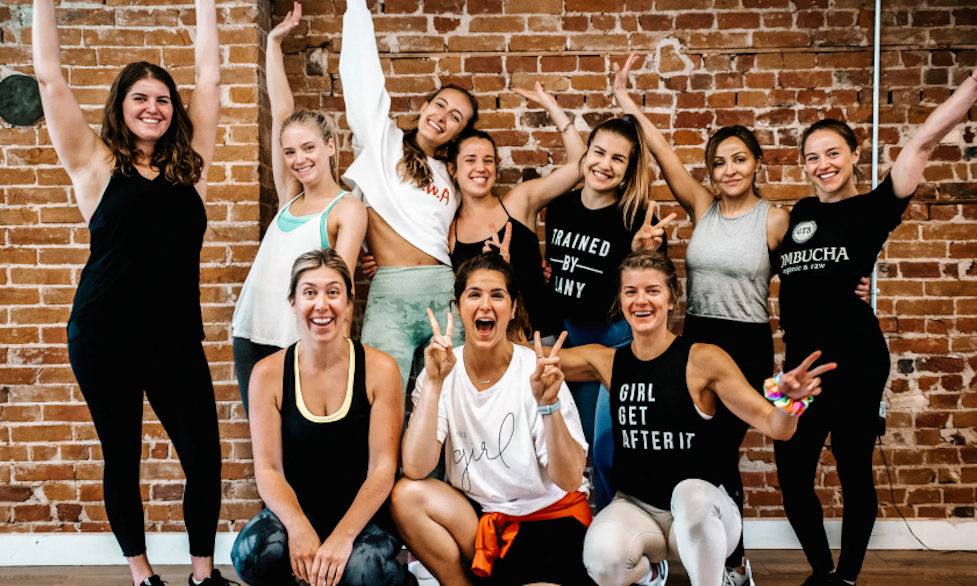 A group of women cheering in front of a brick wall