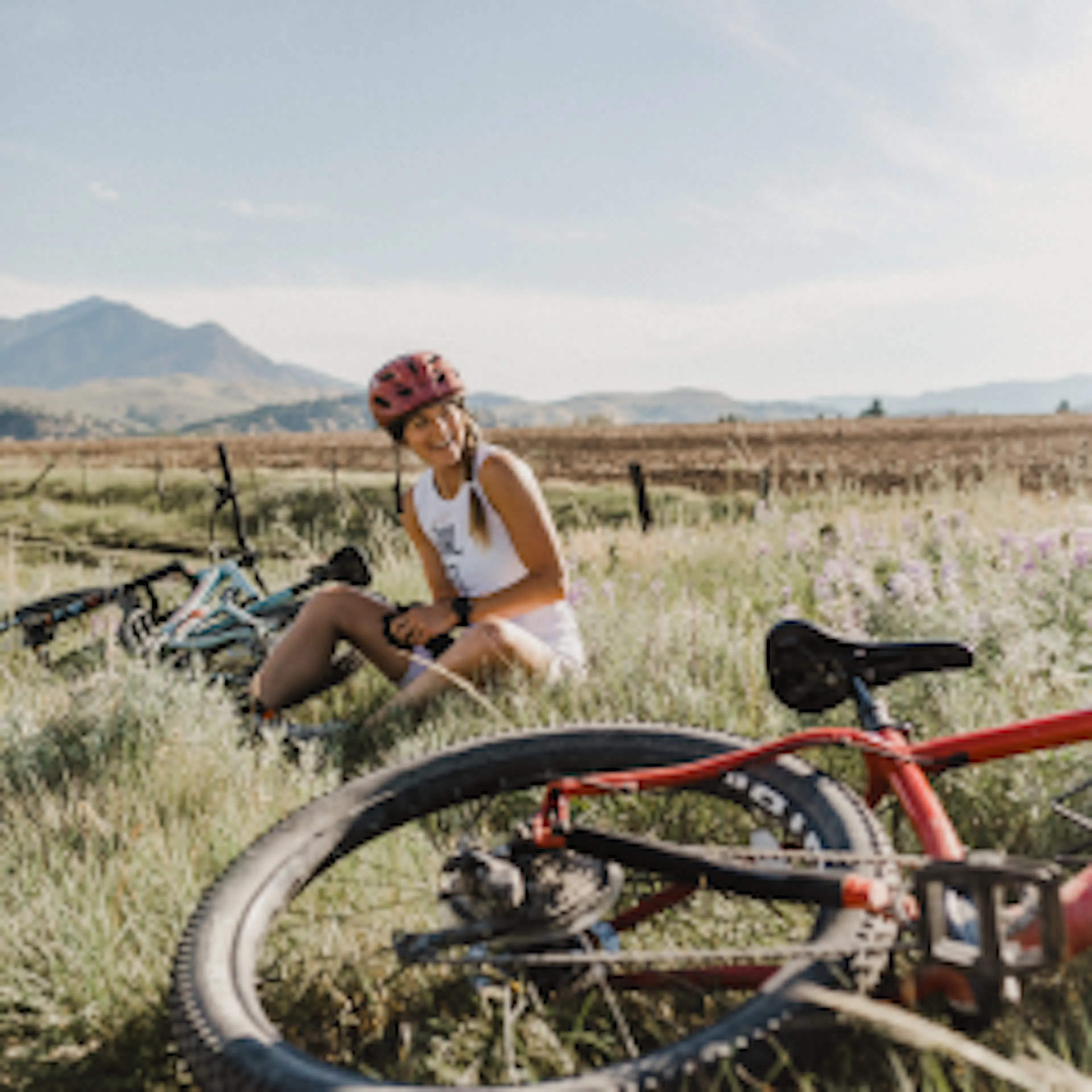 A woman resting in a meadow beside her mountain bike