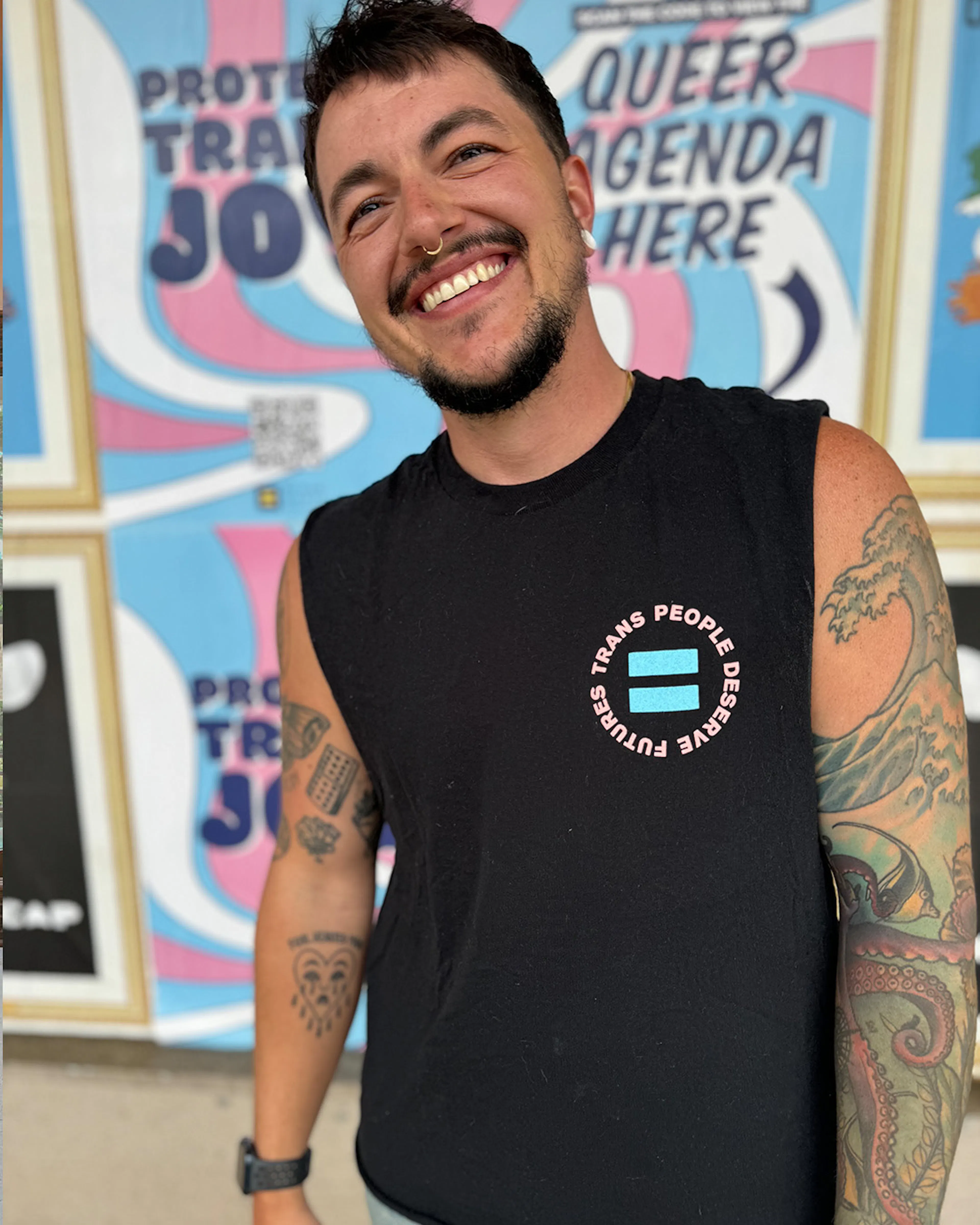 Chris Rhodes smiling in a “Trans people deserve futures” tank top