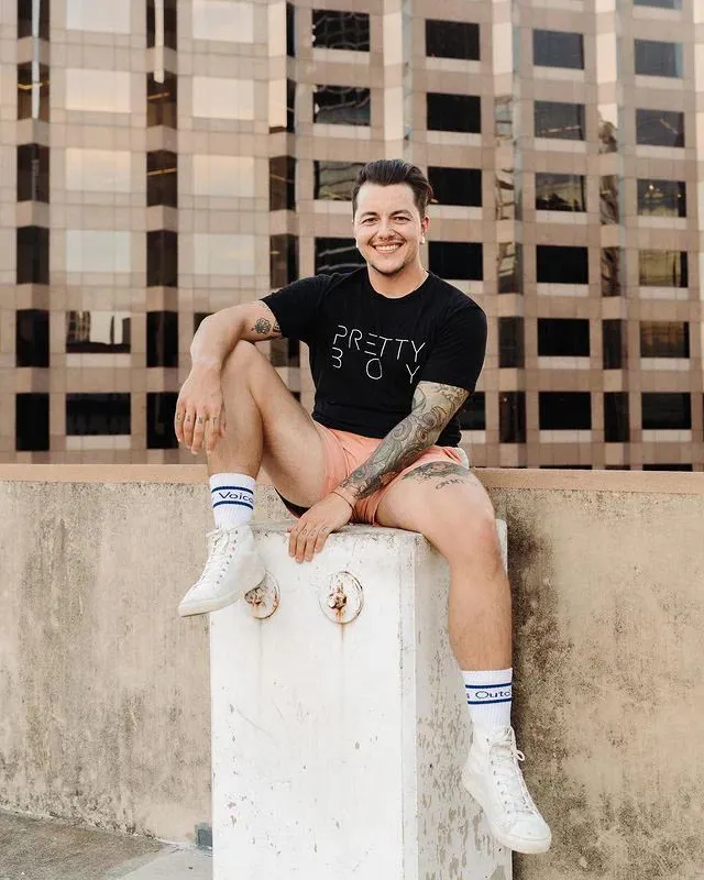 Chris Rhodes sitting on a concrete ledge in a Pretty Boy T-shirt