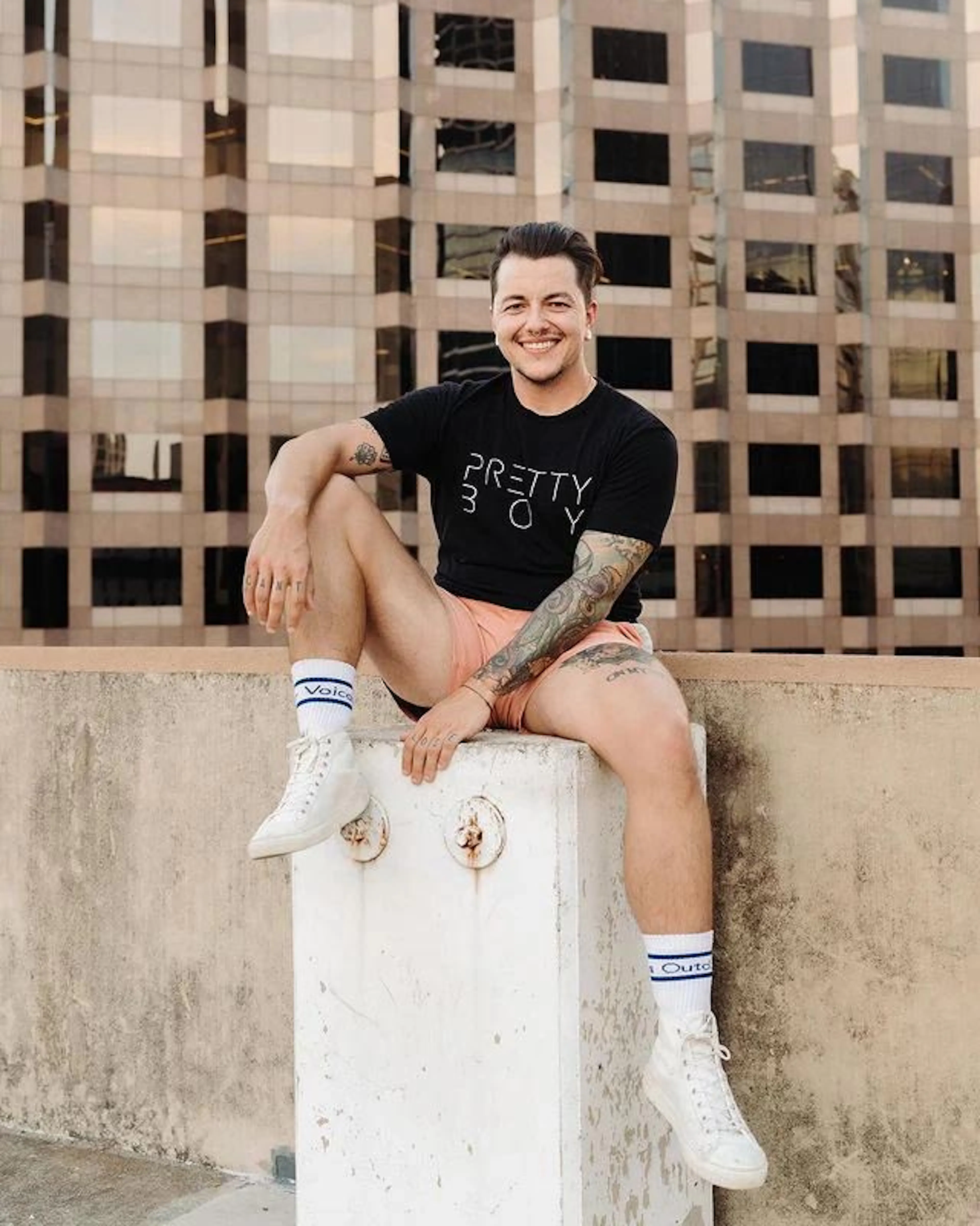 Chris Rhodes sitting on a concrete ledge in a Pretty Boy T-shirt