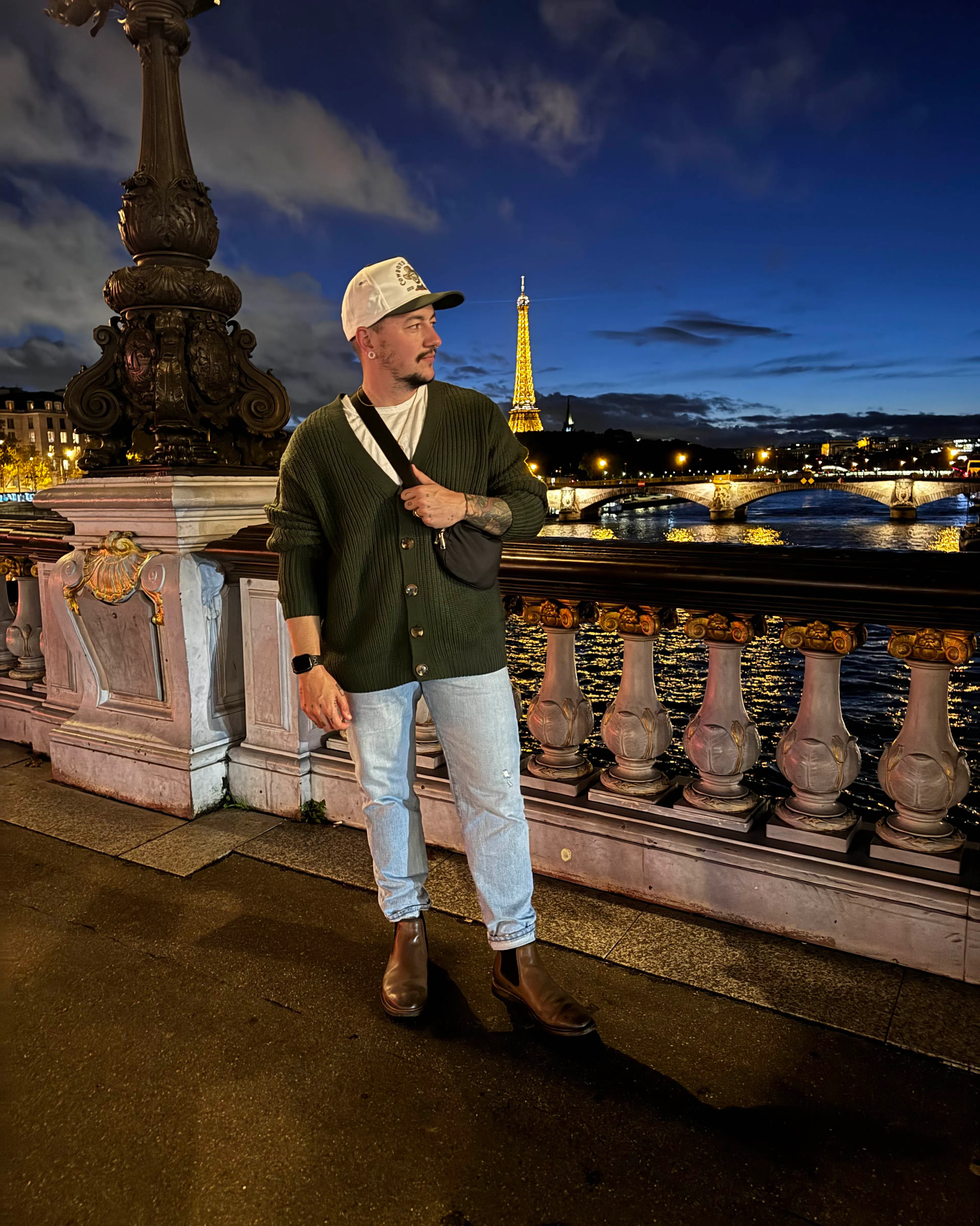 Chris Rhodes on a bridge at night with the Eiffel Tower in the distance