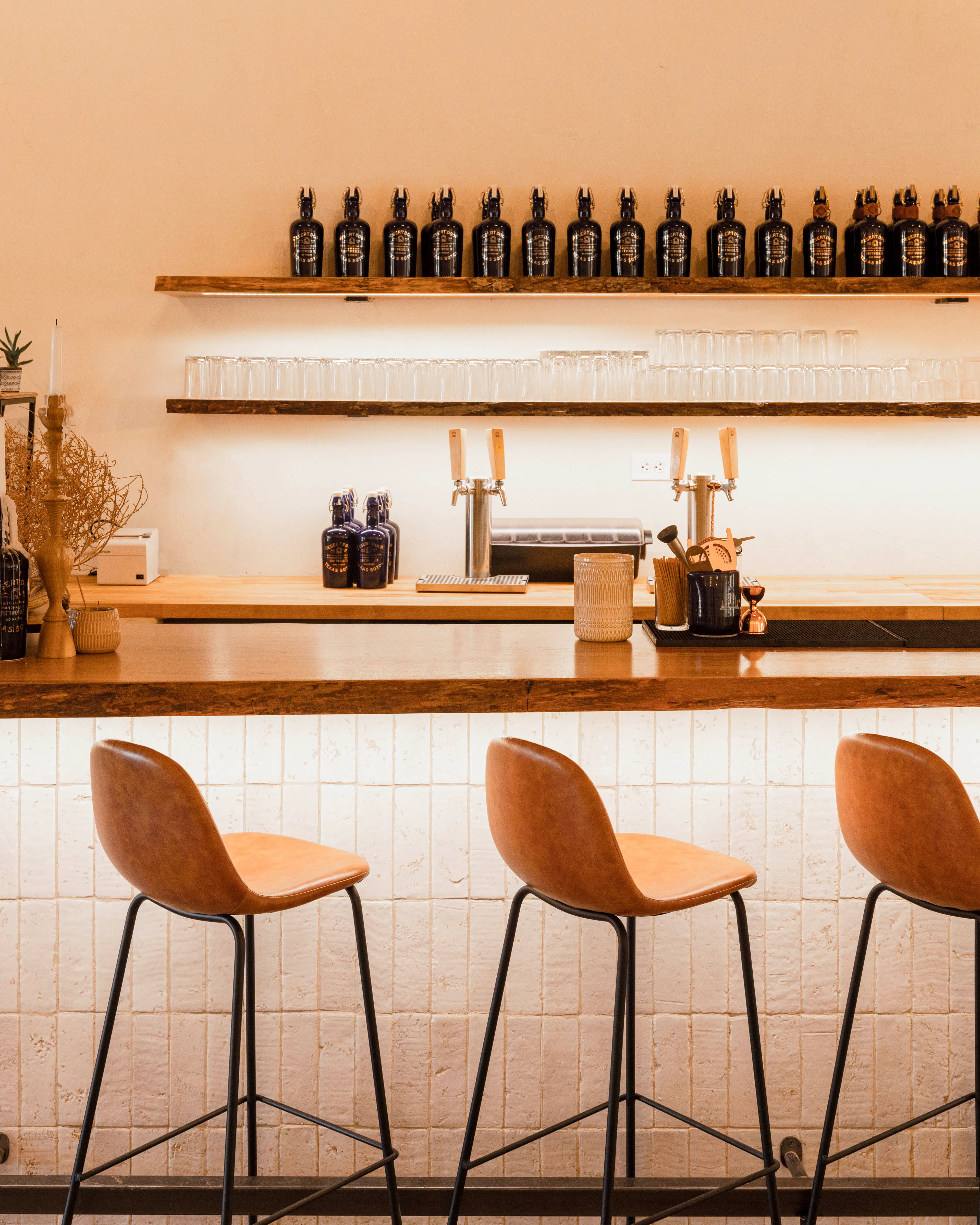 Bar stools at the Desert Door bar, with bottles on the shelves behind