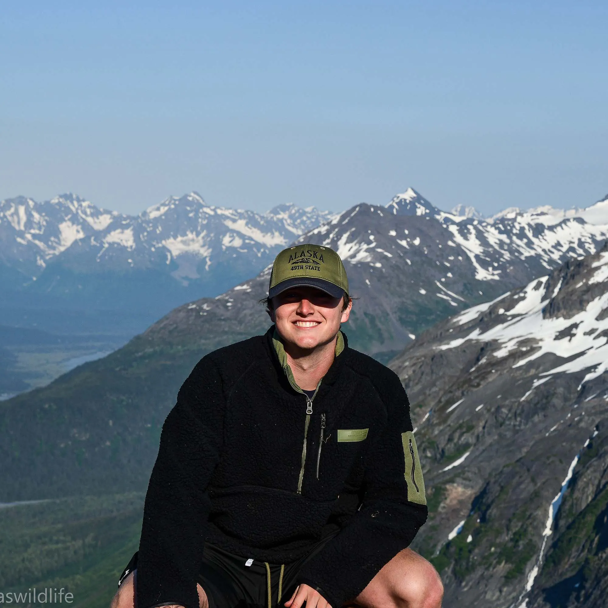 Jack Nailor kneeling in front of snow-capped mountains