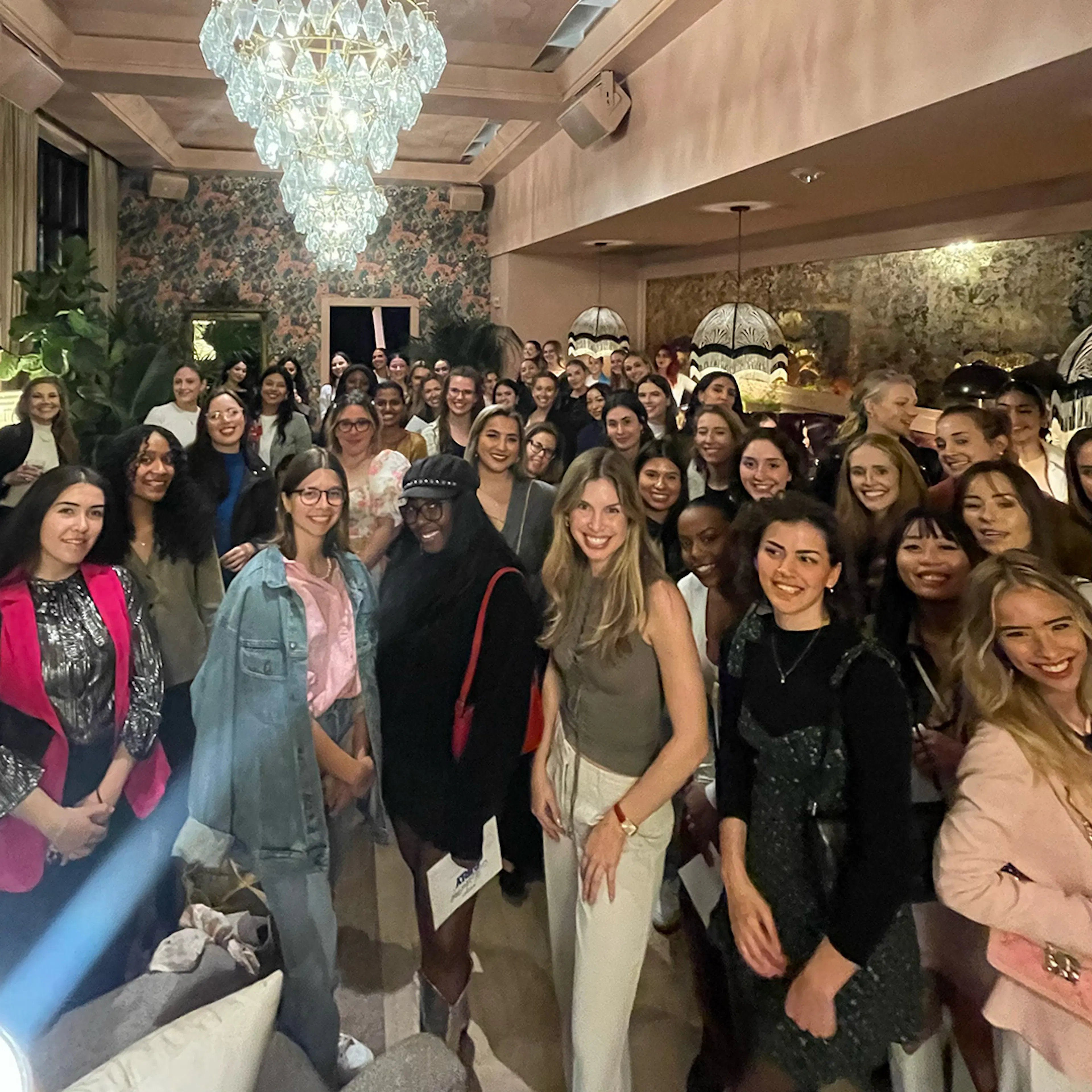 A large group of women at a Sky Society event under chandeliers