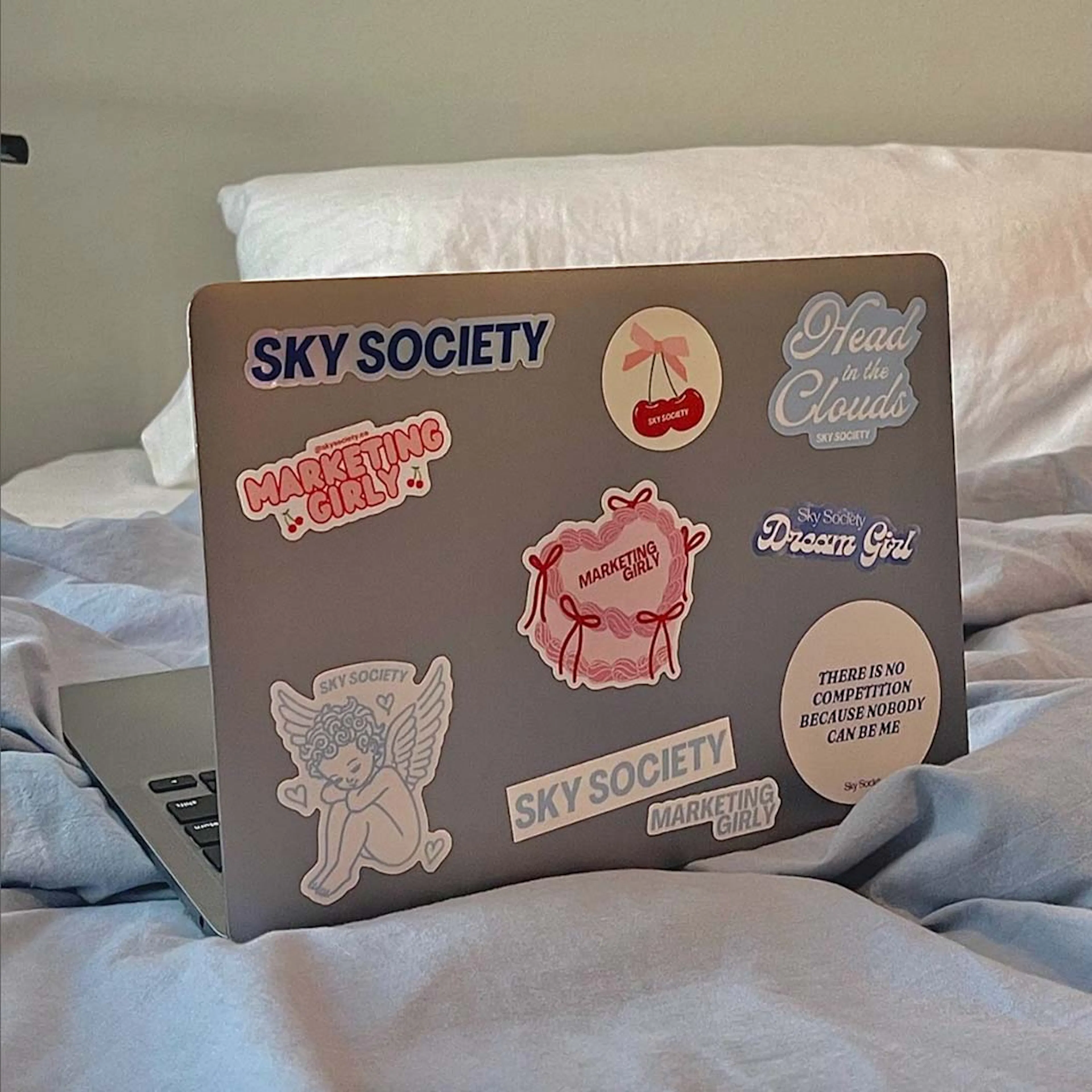 A laptop covered in Sky Society and Marketing Girly stickers