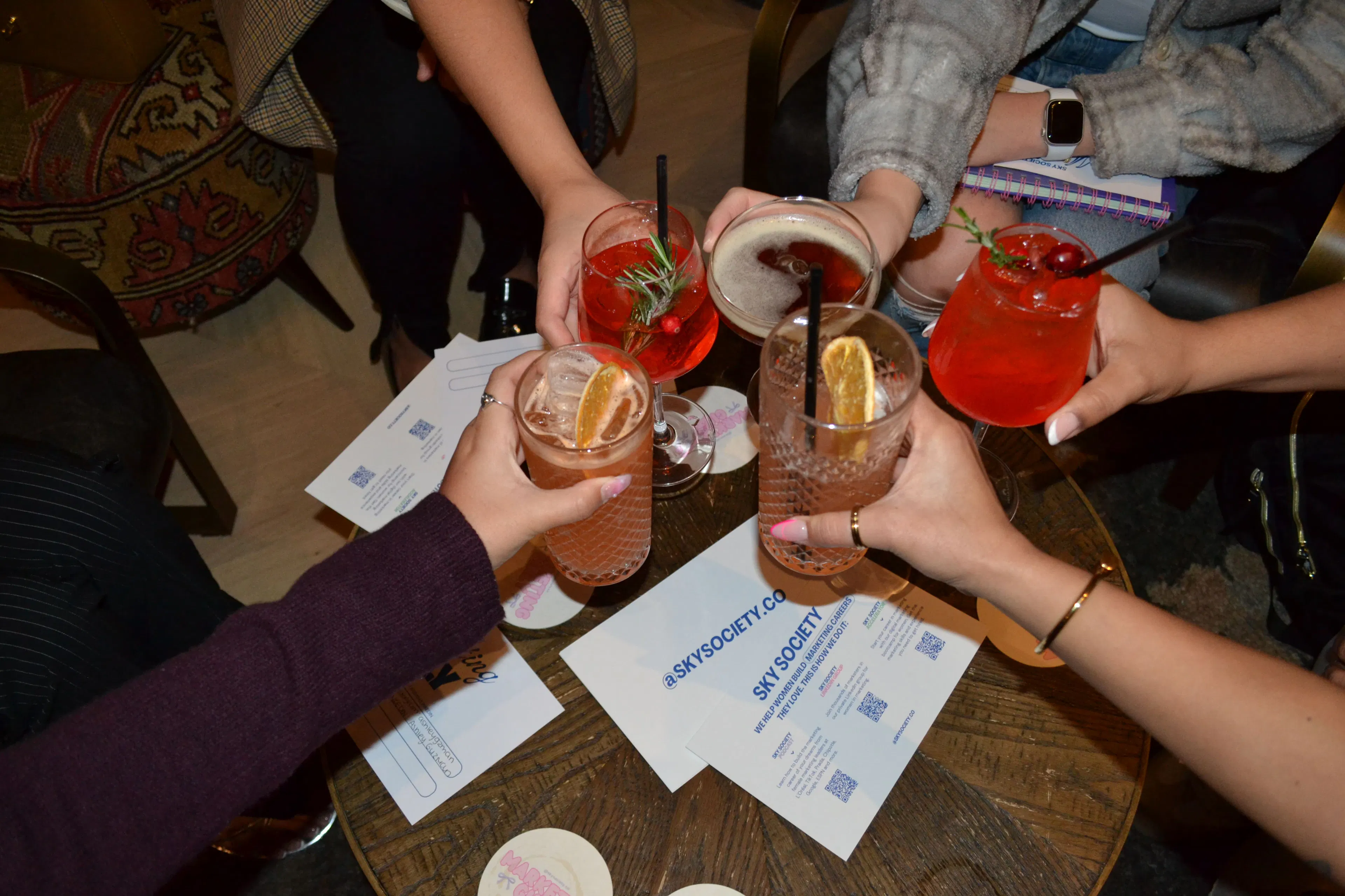 Guests raising cocktails together over a table at an event