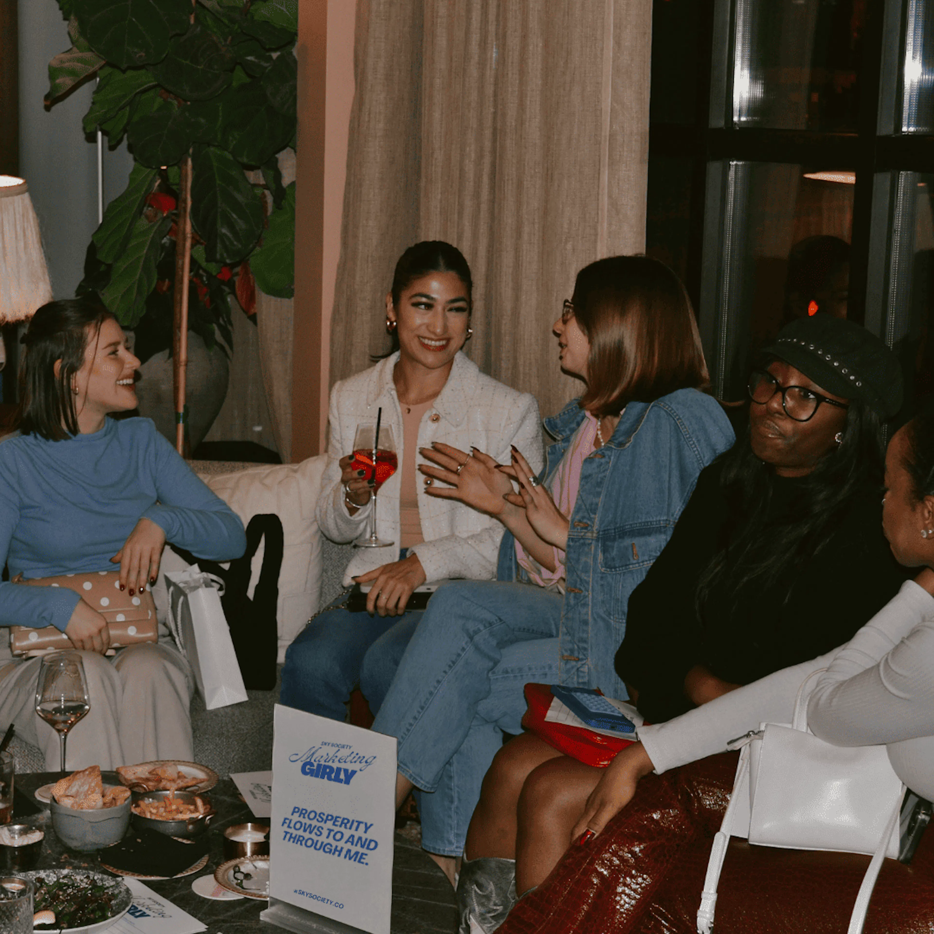 Women talking and laughing on sofas at a Sky Society event