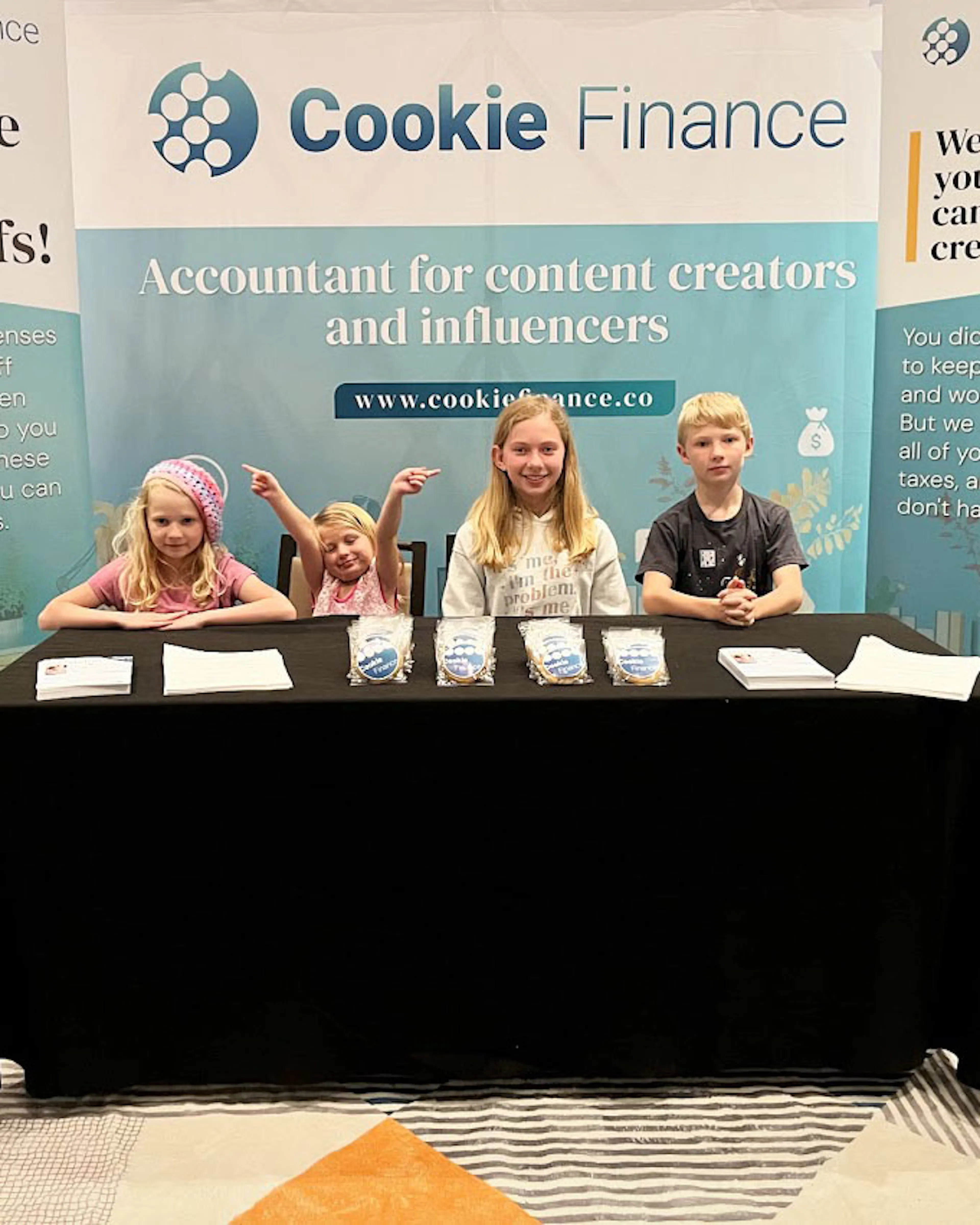 Four children sitting behind the Cookie Finance booth table