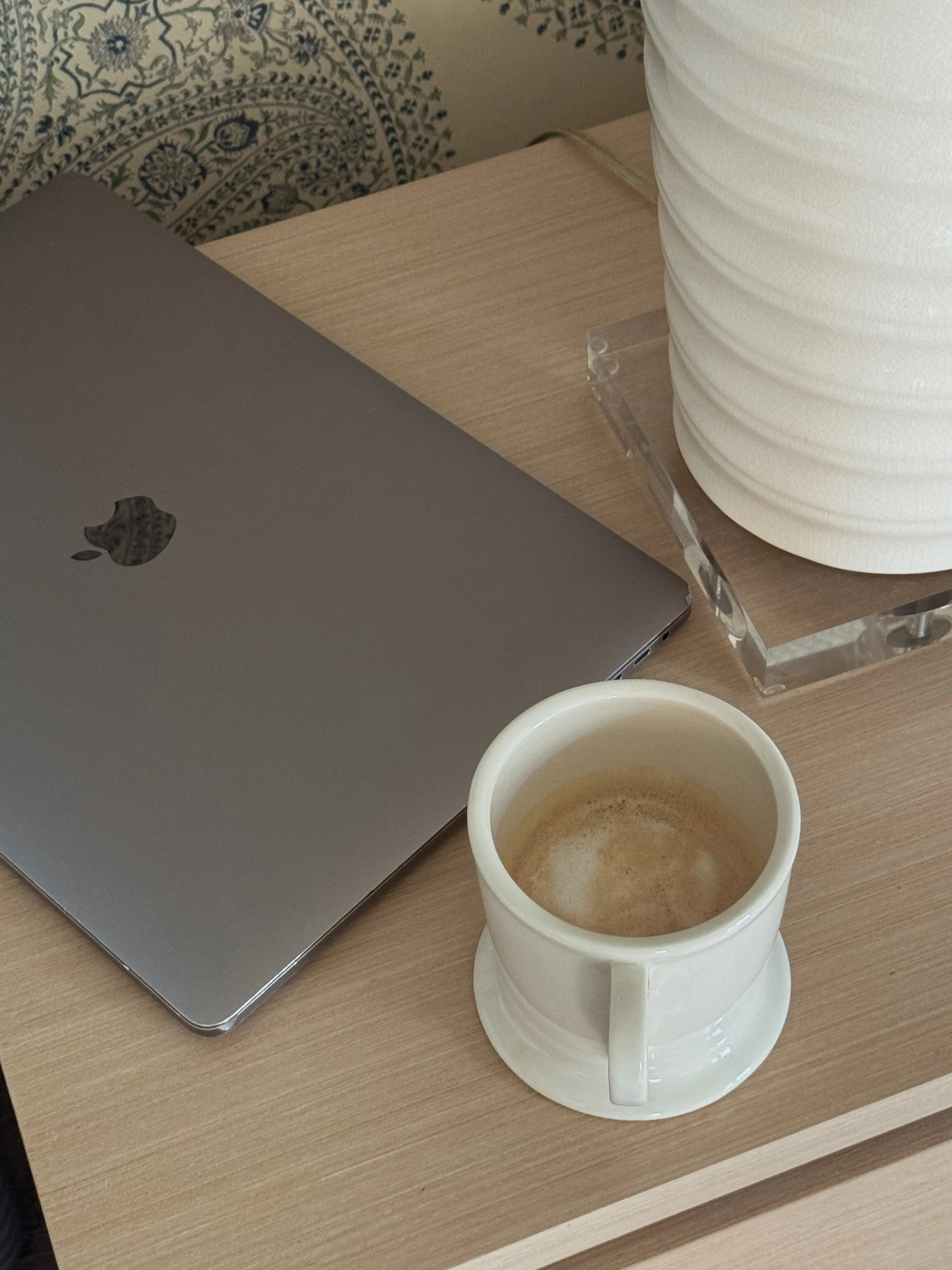 A laptop and a cup of coffee on a wooden desk
