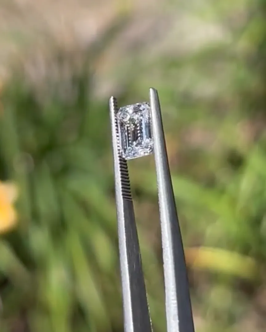 Tweezers holding an emerald-cut diamond