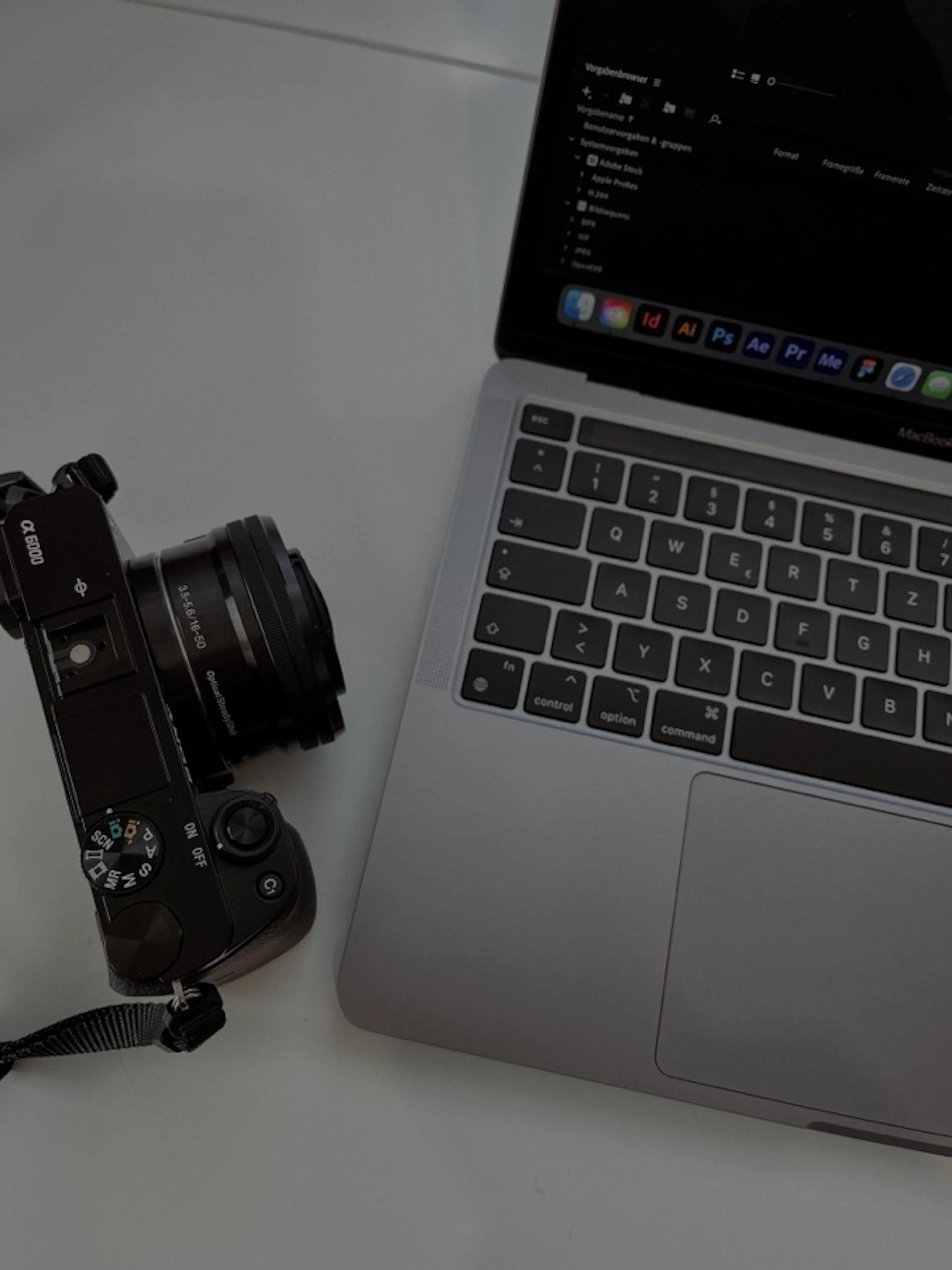 A mirrorless camera on a desk beside an open laptop.